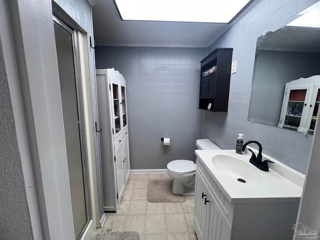 bathroom featuring vanity, crown molding, tile walls, toilet, and a shower with shower door