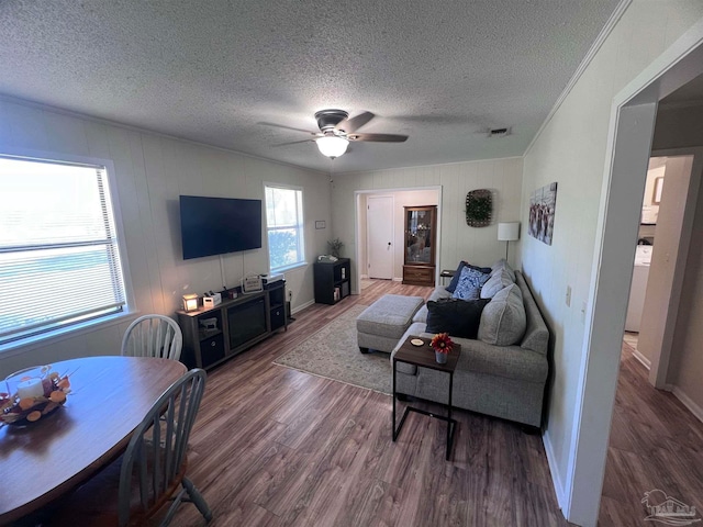 living room with ornamental molding, a textured ceiling, ceiling fan, wood-type flooring, and washer / dryer