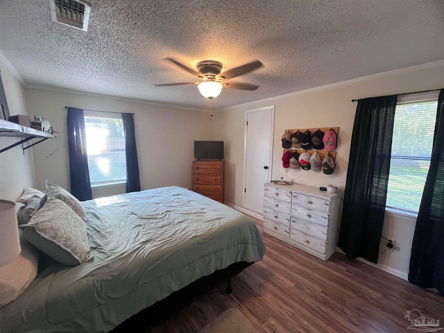 bedroom featuring hardwood / wood-style floors, ceiling fan, ornamental molding, and a textured ceiling