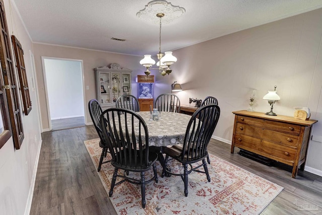 dining area with crown molding, a textured ceiling, a chandelier, and wood finished floors