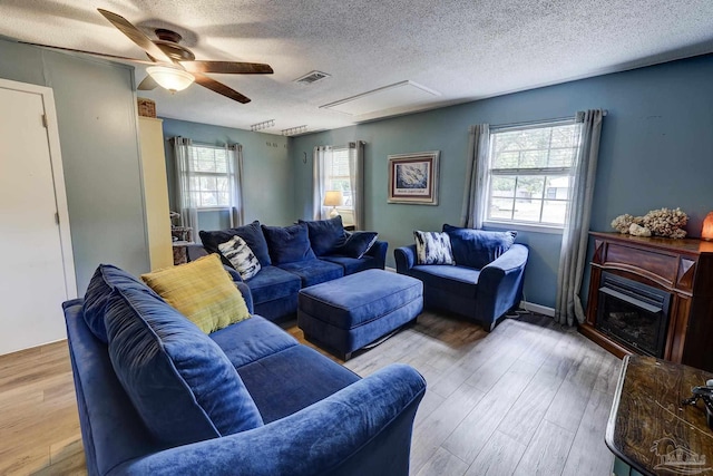 living area featuring a healthy amount of sunlight, attic access, a textured ceiling, and visible vents