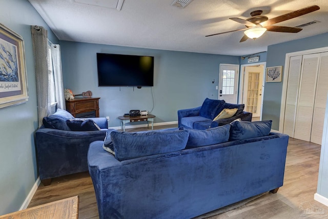 living room with a ceiling fan, baseboards, visible vents, and wood finished floors