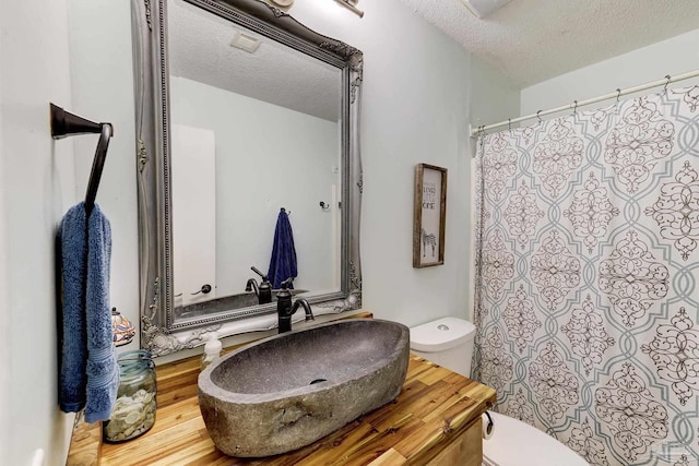 full bathroom with vanity, a textured ceiling, toilet, and a shower with curtain