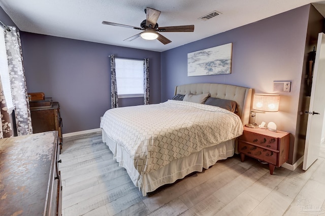 bedroom with baseboards, visible vents, ceiling fan, and light wood finished floors