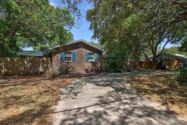 view of side of home with brick siding, fence, and driveway