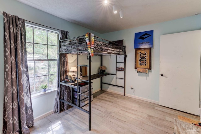 bedroom with track lighting, baseboards, and wood finished floors