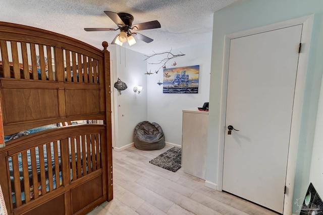 bedroom with baseboards, ceiling fan, light wood-type flooring, and a textured ceiling