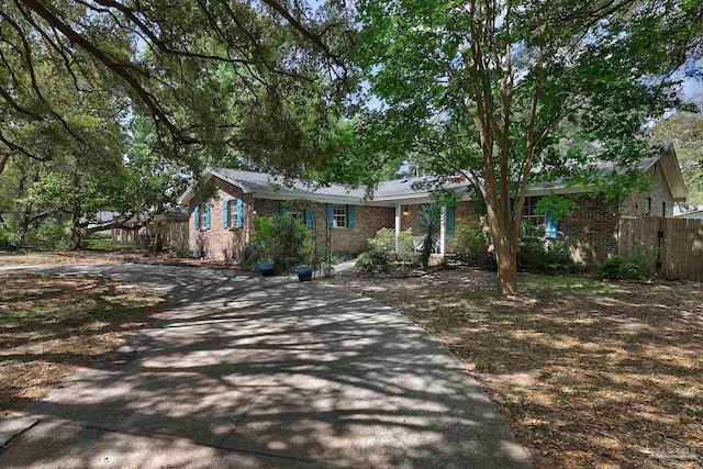 single story home featuring brick siding, fence, and aphalt driveway