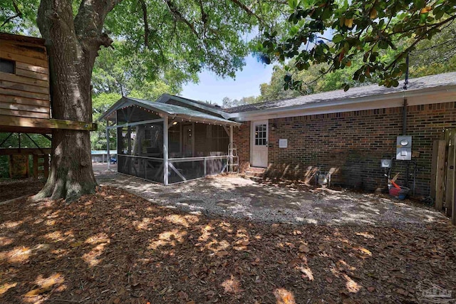 rear view of house with a sunroom and brick siding