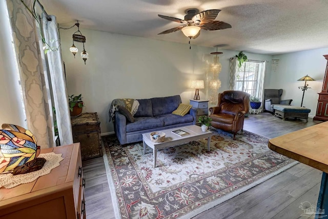 living area with a ceiling fan, a textured ceiling, and wood finished floors