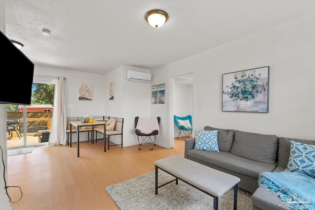 living room featuring a textured ceiling, an AC wall unit, and wood finished floors