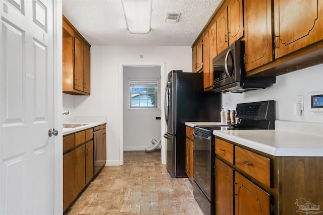 kitchen featuring appliances with stainless steel finishes, sink, a textured ceiling, and light hardwood / wood-style floors