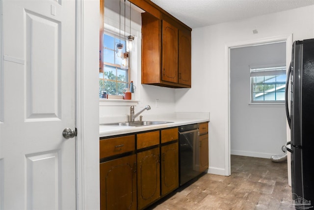 kitchen with black fridge, sink, hanging light fixtures, and a wealth of natural light