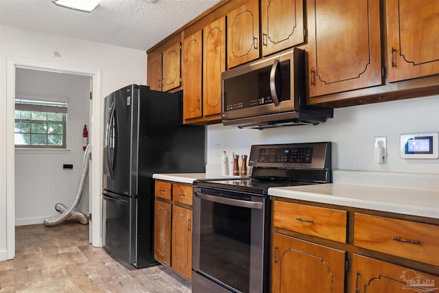 kitchen featuring light hardwood / wood-style flooring, stainless steel appliances, and a textured ceiling