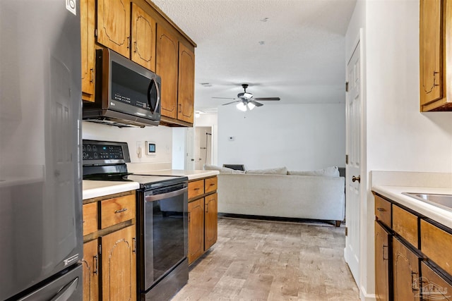 kitchen with a textured ceiling, light hardwood / wood-style floors, ceiling fan, and appliances with stainless steel finishes