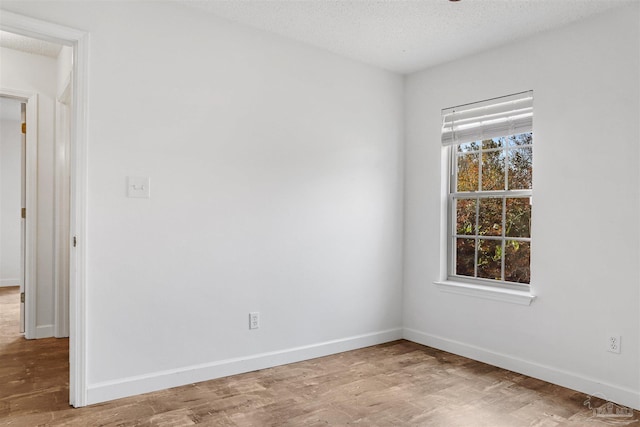 unfurnished room with hardwood / wood-style flooring and a textured ceiling