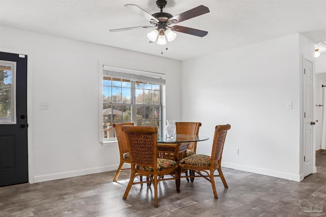 dining room featuring dark wood-type flooring, ceiling fan, and a textured ceiling