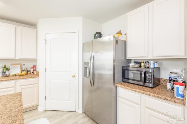 kitchen featuring white cabinets, stainless steel appliances, and light wood-type flooring