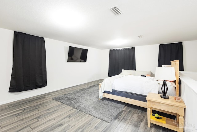 bedroom with visible vents, baseboards, and wood finished floors