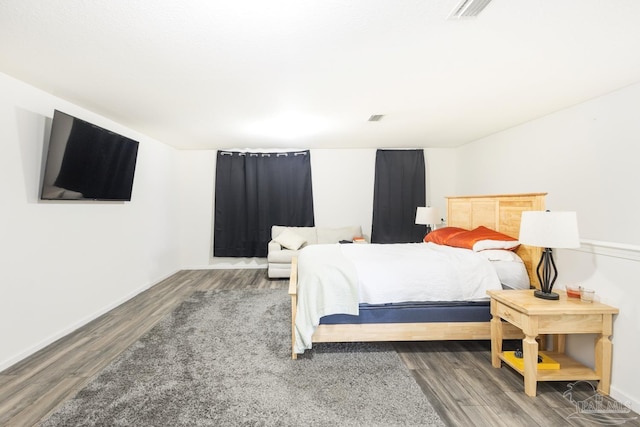 bedroom featuring visible vents, baseboards, and wood finished floors