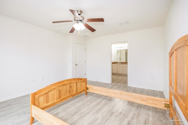 unfurnished bedroom featuring light wood-style flooring, a ceiling fan, ensuite bathroom, and baseboards