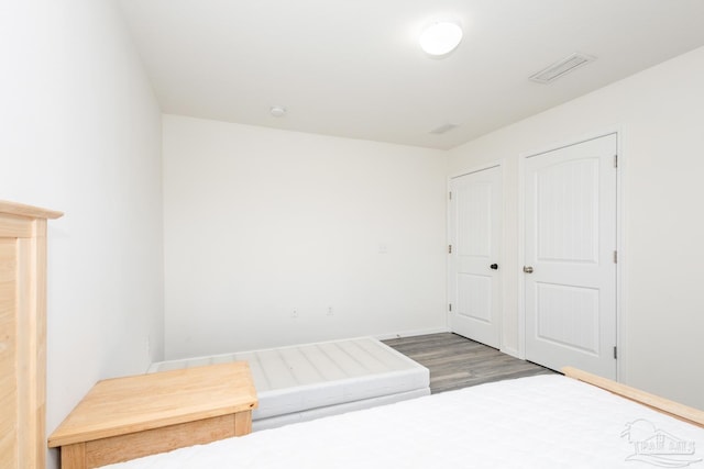 unfurnished bedroom featuring visible vents, baseboards, and wood finished floors