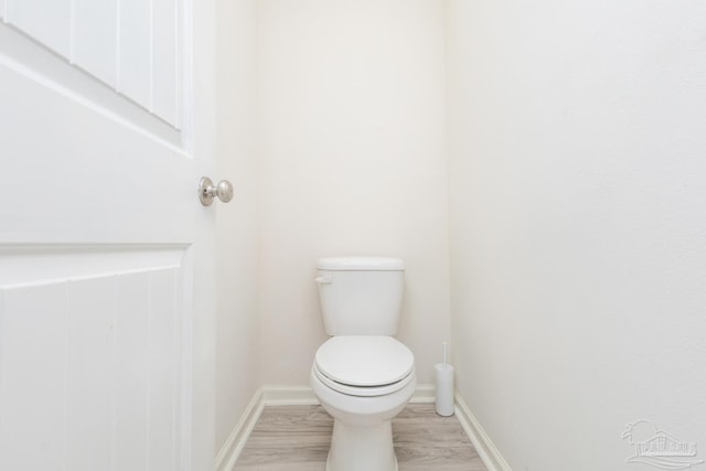 bathroom with baseboards, toilet, and wood finished floors