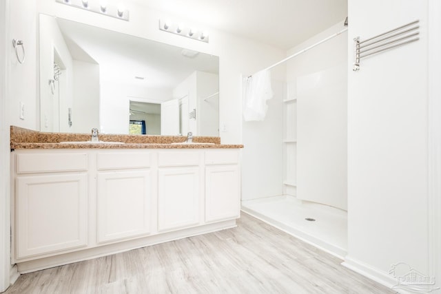 full bathroom featuring a sink, a shower with shower curtain, and wood finished floors