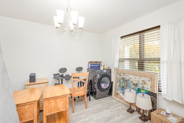 clothes washing area featuring washing machine and clothes dryer, laundry area, an inviting chandelier, and wood finished floors