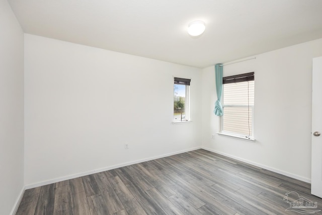 spare room featuring dark wood-type flooring and baseboards