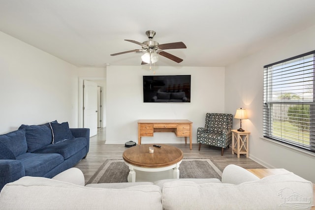 living area featuring baseboards, a ceiling fan, and wood finished floors