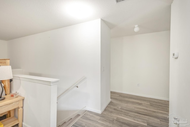 hallway featuring an upstairs landing, light wood-style flooring, and baseboards