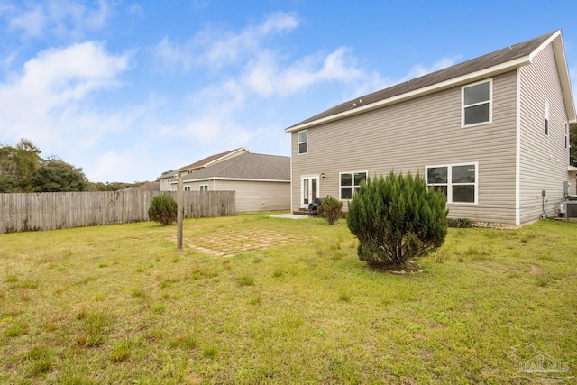 back of house featuring central AC unit, a yard, and fence