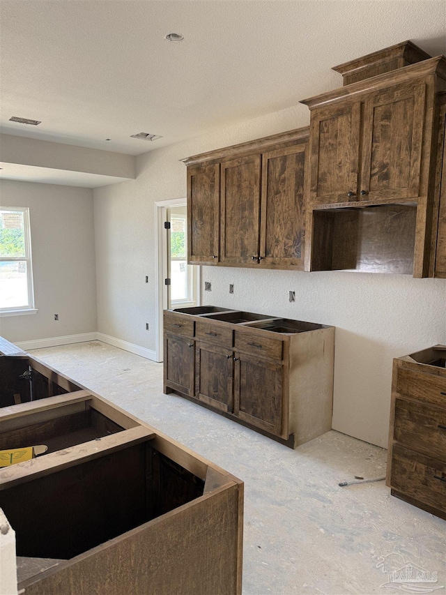 kitchen featuring dark brown cabinets, visible vents, and a healthy amount of sunlight