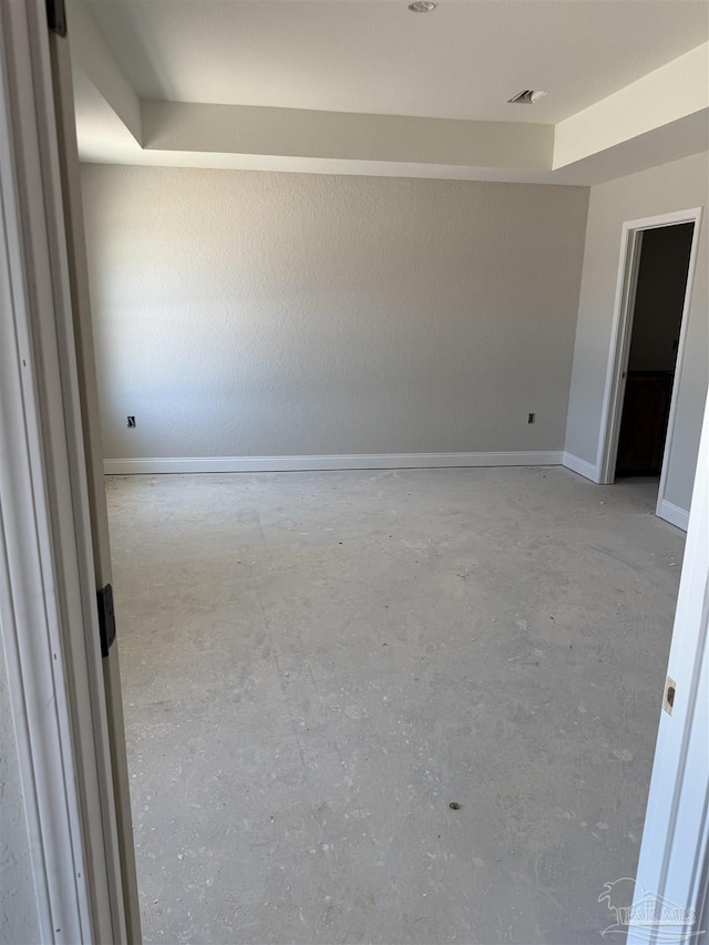 empty room featuring concrete flooring, visible vents, and baseboards