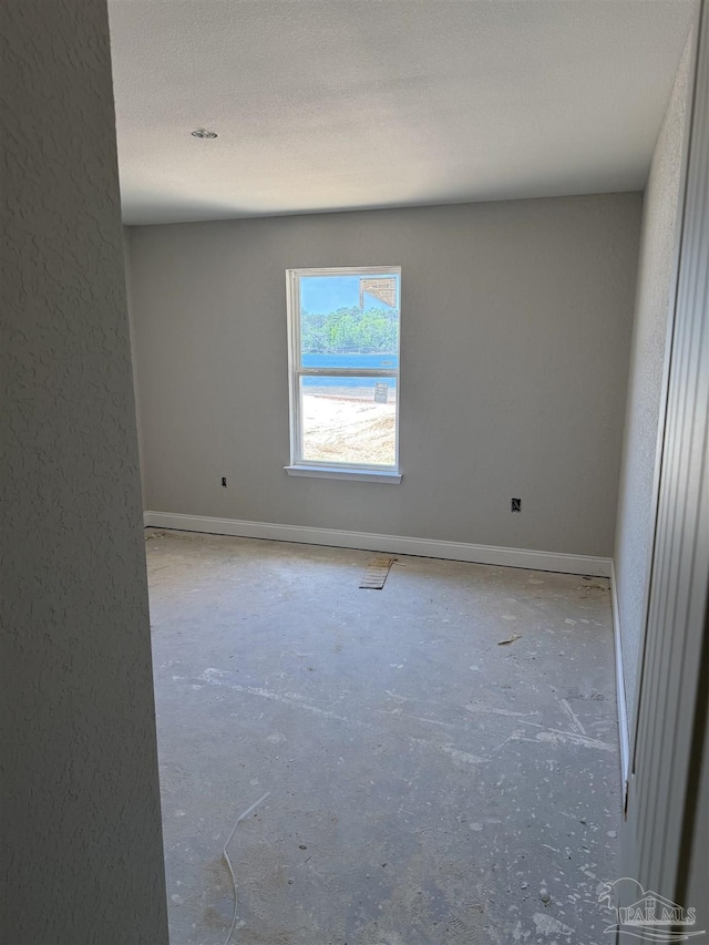 unfurnished room featuring unfinished concrete flooring and baseboards
