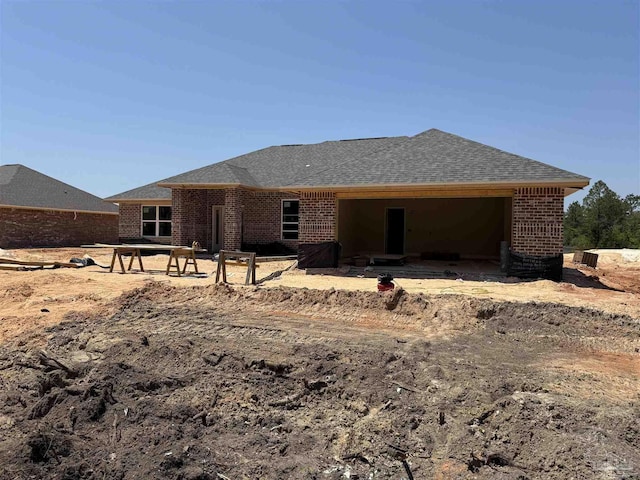 back of house with brick siding and a shingled roof