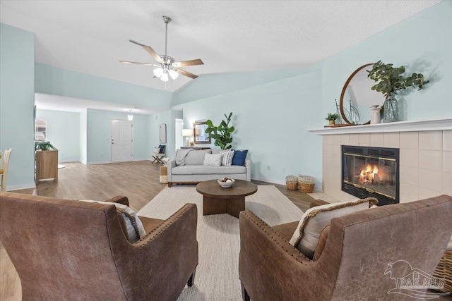 living room with wood-type flooring, a fireplace, vaulted ceiling, and ceiling fan