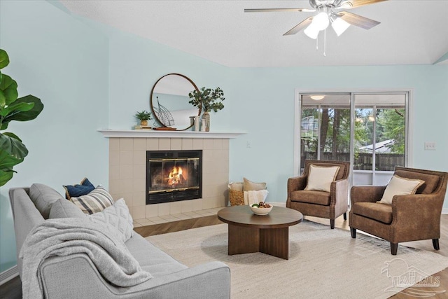 living room featuring a tile fireplace, ceiling fan, and hardwood / wood-style flooring