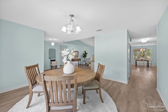 dining space featuring a textured ceiling, an inviting chandelier, and hardwood / wood-style flooring