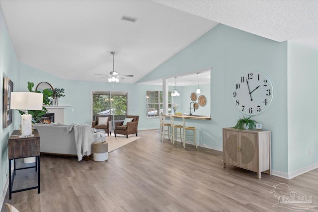 living room featuring ceiling fan, light hardwood / wood-style floors, and high vaulted ceiling