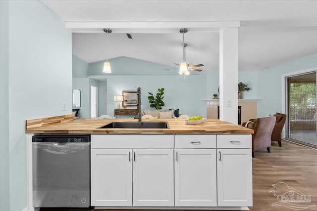 kitchen with dishwasher, sink, vaulted ceiling, white cabinetry, and decorative light fixtures