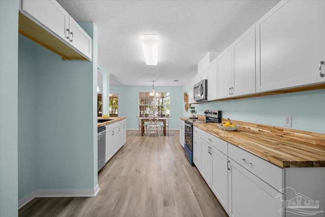 kitchen with light hardwood / wood-style flooring, butcher block countertops, white cabinets, and appliances with stainless steel finishes