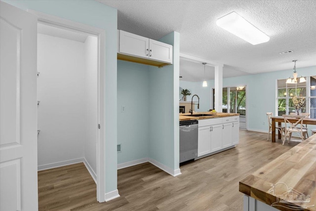 kitchen with pendant lighting, dishwasher, wooden counters, and white cabinetry