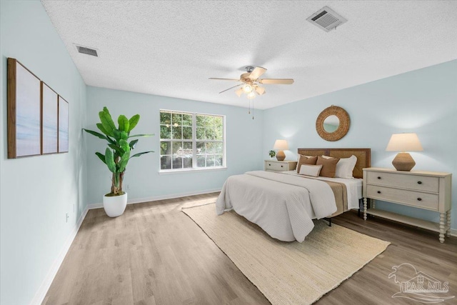 bedroom featuring a textured ceiling, hardwood / wood-style floors, and ceiling fan