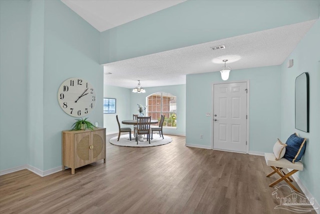 foyer with an inviting chandelier, a textured ceiling, and hardwood / wood-style floors