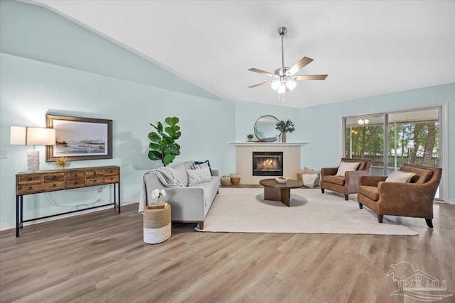 living room with ceiling fan, lofted ceiling, hardwood / wood-style floors, and a tile fireplace