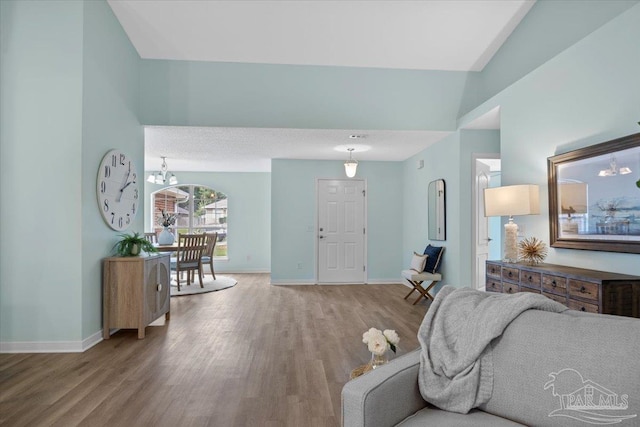 living room featuring vaulted ceiling, a notable chandelier, and light hardwood / wood-style floors