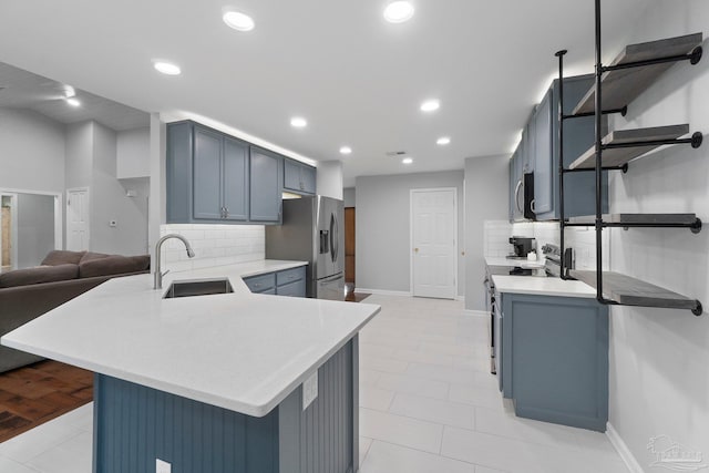 1052 Ashley Rd, Milton, FL 32583 - kitchen with a sink, stainless steel appliances, a peninsula, blue cabinets, and backsplash