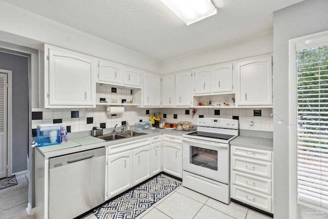 kitchen featuring light tile patterned floors, white range with electric cooktop, white cabinets, and stainless steel dishwasher